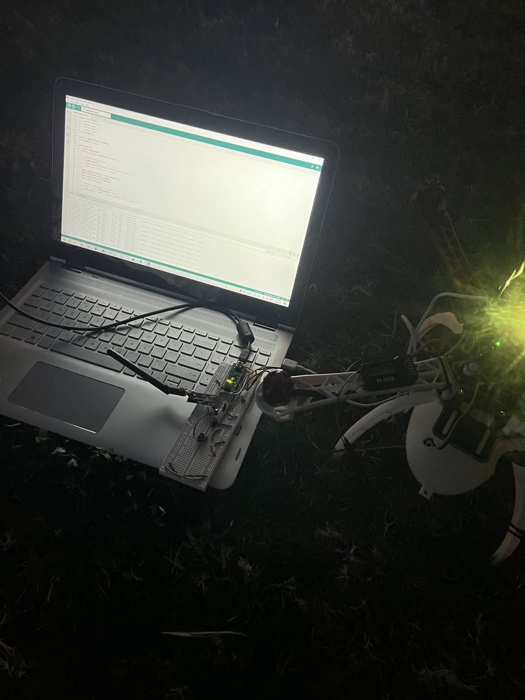 Night range test: laptop and breadboard relay on the grass beside the powered-up aircraft.